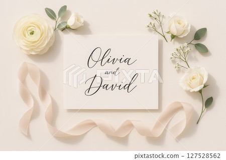 Wedding invitation card with names surrounded by white roses, ranunculus, leaves and ribbon on light background 127528562