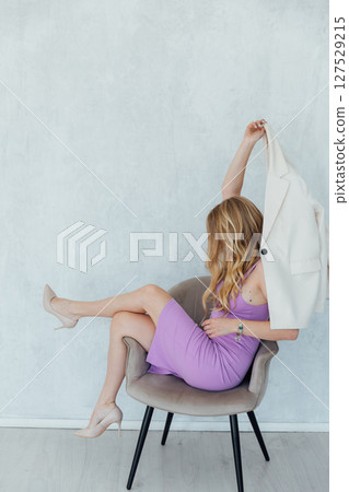 Beautiful woman in purple dress on chair laughing 127529215