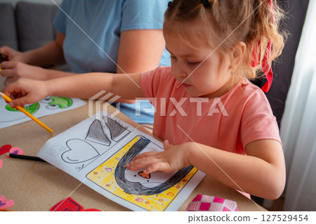 Portrait of little cute girl decorate Valentine's Day cards, sitting at table. Concept of St. Valentine Day and family leisure 127529454