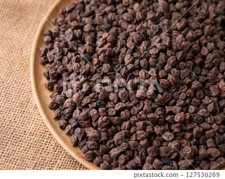 Raw Dark Brown Chickpeas (Kala Chana) on a rustic wooden table. Dry Balck chickpea (ceci neri) background close up. 127530269