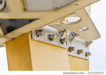 Bolted gusset plates securing yellow steel beam to column, structural engineering close up Bolted gusset plates securing yellow steel beam to column, structural engineering close up 127530743