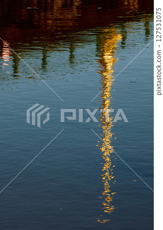 Reflection of the Peter and Paul Fortress spire on water surface at sunset 127531075