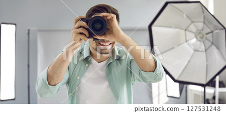 Young male photographer using professional camera in studio 127531248