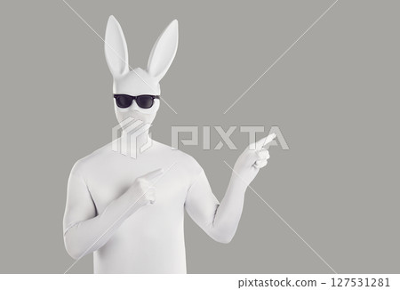 Faceless unrecognizable person in black sunglasses and hare mask pointing index finger to the side. Faceless unrecognizable person in black sunglasses and hare mask pointing index finger to the side. 127531281