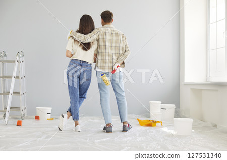Couple Embracing While Painting Walls During Home Renovation Couple Embracing While Painting Walls During Home Renovation 127531340