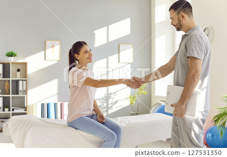 Smiling Physiotherapist Shaking Hands With Happy Patient In Office Smiling Physiotherapist Shaking Hands With Happy Patient In Office 127531350