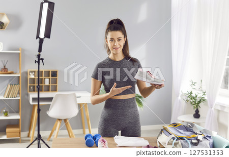 Female blogger is showing sports shoes and equipment, preparing to create content about workout. Female blogger is showing sports shoes and equipment, preparing to create content about workout. 127531353
