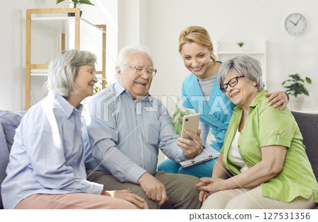 A group of old people making a video call from a smartphone in a guesthouse A group of old people making a video call from a smartphone in a guesthouse 127531356
