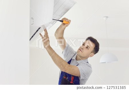 Air conditioner indoor unit installed, qualified installation technician working Air conditioner indoor unit installed, qualified installation technician working 127531385