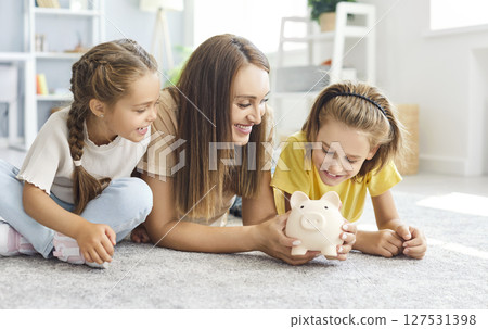 Happy family, kids and mother saving money together, playing with piggy bank, parent, children 127531398