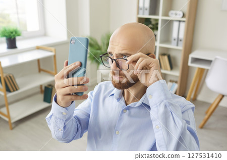 Surprised Man Browsing News On Smartphone While Working In Office Surprised Man Browsing News On Smartphone While Working In Office 127531410