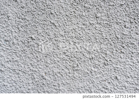 Rough white textured wall provides a detailed closeup of its uneven surface, suitable for backgrounds or design work. Unique structure and simplicity, it's ideal for creative projects 127531494