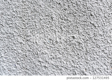 Rough white textured wall provides a detailed closeup of its uneven surface, suitable for backgrounds or design work. Unique structure and simplicity, it's ideal for creative projects 127531495