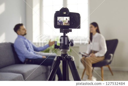 Close up photo of professional camera recording live podcast video interview of two bloggers. Close up photo of professional camera recording live podcast video interview of two bloggers. 127532484