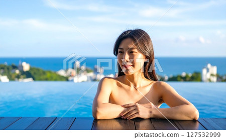 一位女士在溫泉中沐浴，望著大海 127532999