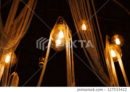 Unique hanging lights create a warm ambiance in an artistic space, enhancing relaxation and creativity Unique hanging lights create a warm ambiance in an artistic space, enhancing relaxation and creativity 127533422