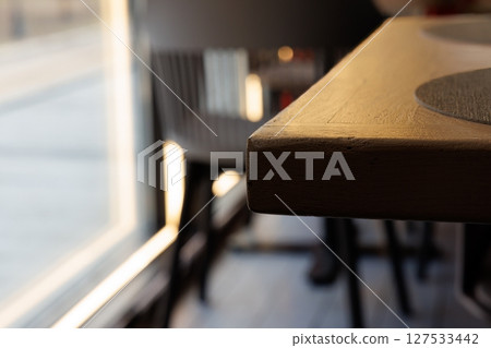 Warm sunlight bathes a rustic wooden table in a cozy cafe during afternoon hours 127533442
