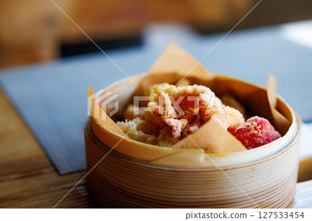 Delicious assortment of crispy Chinese food served in a traditional bamboo steamer at a cozy restaurant 127533454