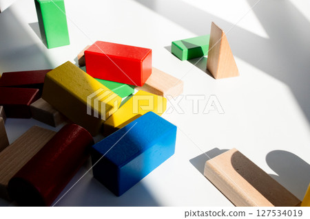Colorful wooden building blocks on sunlit surface 127534019