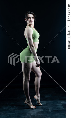 Athletic woman standing on black background, showing her fit body 127534246