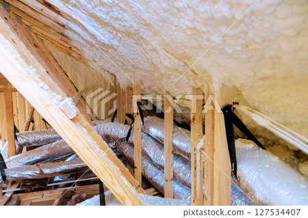 Insulation installation process in an attic with exposed wooden beams ductwork in residential building Insulation installation process in an attic with exposed wooden beams ductwork in residential building 127534407