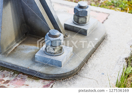 Heavy Duty Steel Bolts Securing Industrial Metal Structure to Concrete Base 127536169