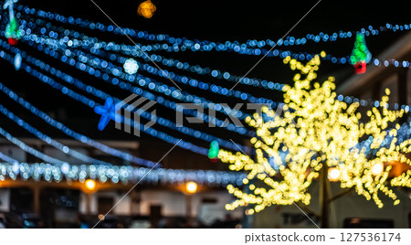 creative colorful background with blurred defocused christmas and new year lights, bokeh of multicolored garland and illumination 127536174