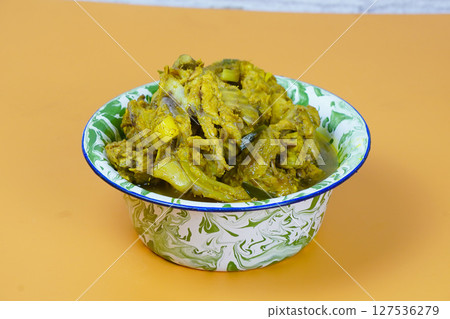 A vibrant bowl of Indonesian soto tulang ayam or chicken bones spicy soup, rich in yellow spices, sits on an orange background A vibrant bowl of Indonesian soto tulang ayam or chicken bones spicy soup, rich in yellow spices, sits on an orange background 127536279