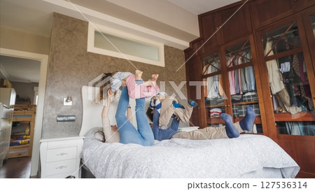 Happy family playing on bed lifting children in bedroom Happy family playing on bed lifting children in bedroom 127536314
