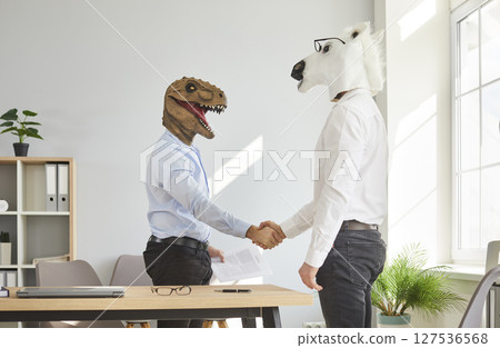 Two colleagues in animal head masks handshaking after meeting 127536568