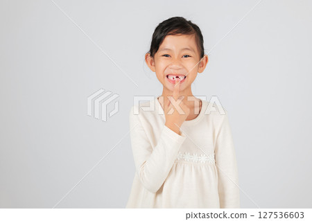 Happy child pointing to a tooth gap with joy. The dentist discusses tooth loss and the importance of monitoring the growing tooth gap for healthy teeth. isolated white background 127536603
