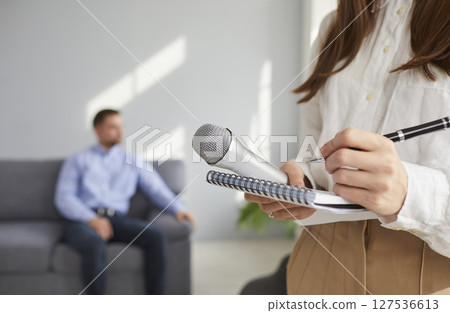 Journalist or TV correspondent with notepad, pen and mic in hands gets ready for interview 127536613