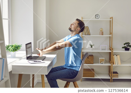 Relaxed tired business man resting and stretching arms at the desk relaxing at office. Relaxed tired business man resting and stretching arms at the desk relaxing at office. 127536614