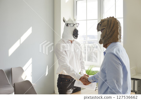 Two businessmen in animal head masks shaking hands 127536662