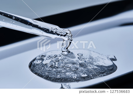 The texture of serum with spicules in a dropper on a blue background. The texture of serum with spicules in a dropper on a blue background. 127536683