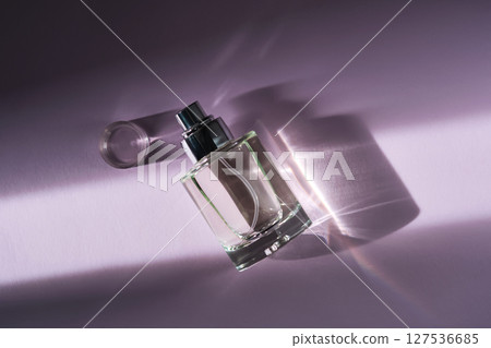 Perfume in the rays of bright sun with beautiful highlights. Purple background. 127536685