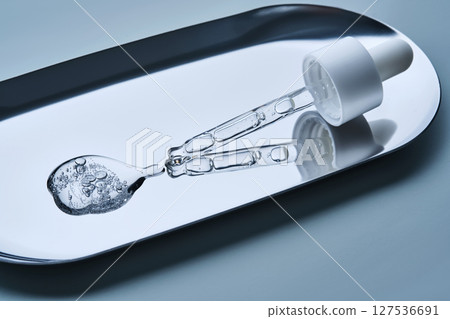 The texture of cosmetic serum in a pipette on a blue background. The texture of cosmetic serum in a pipette on a blue background. 127536691