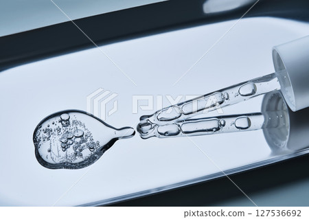 The texture of serum with spicules in a dropper on a blue background. The texture of serum with spicules in a dropper on a blue background. 127536692