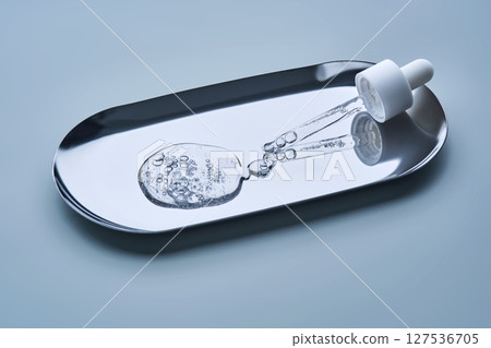 The texture of serum with spicules in a dropper on a blue background. The texture of serum with spicules in a dropper on a blue background. 127536705