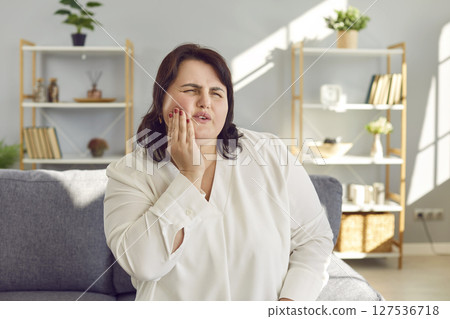 Young overweight woman suffering from toothache and holding her hand on her painful cheek 127536718