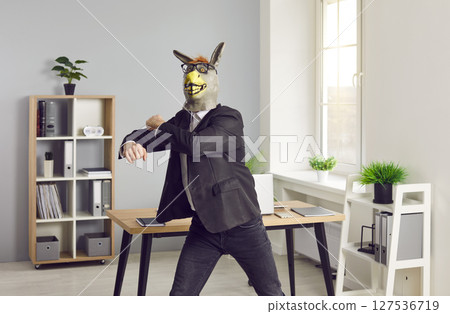 Happy office worker in donkey mask has fun at end of work day, wants to party and dances 127536719
