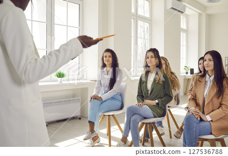 Group of business women on a meeting listening a woman speaking at the conference. 127536788