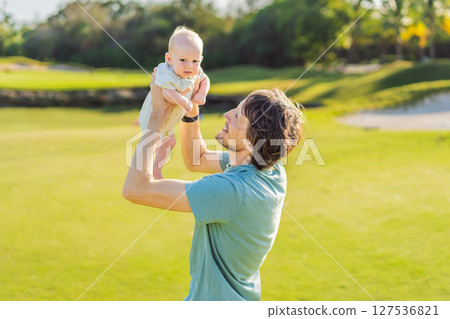 Father and newborn baby on a meadow in the park. Tender moment of bonding and love in nature. Parenthood, fatherhood, and family connection concept Father and newborn baby on a meadow in the park. Tender moment of bonding and love in nature. Parenthood, fatherhood, and family connection concept 127536821