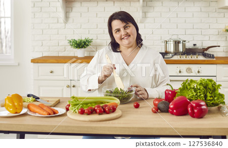 Cheerful overweight woman preparing salad of fresh vegetables Cheerful overweight woman preparing salad of fresh vegetables 127536840