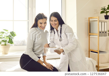Happy young woman doctor and her patient looking at good results of medical tests 127536847