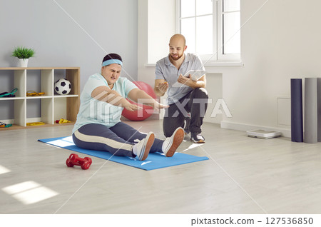 Overweight woman trying to do difficult exercise during workout with personal trainer Overweight woman trying to do difficult exercise during workout with personal trainer 127536850