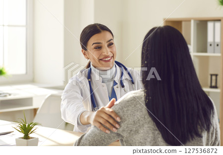 Smiling friendly doctor giving consultation a woman during medical examination in clinic. Smiling friendly doctor giving consultation a woman during medical examination in clinic. 127536872