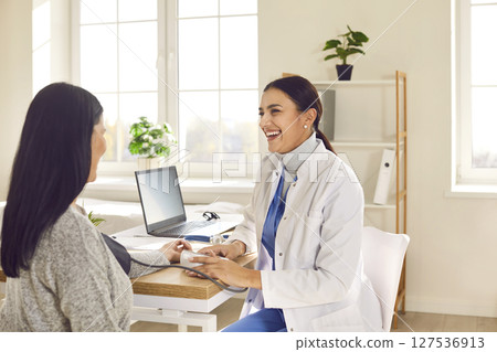 Smiling woman doctor therapist measuring blood pressure of a patient sitting back in the office. Smiling woman doctor therapist measuring blood pressure of a patient sitting back in the office. 127536913