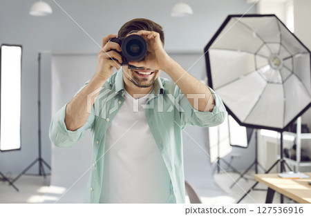 Smiling male professional photographer working in photo studio 127536916