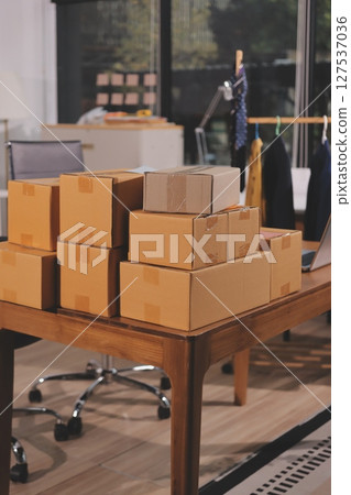 Startup SME small business entrepreneur of freelance Asian woman wearing apron using laptop and box to receive and review orders online to prepare to pack sell to customers, online sme business ideas. 127537036